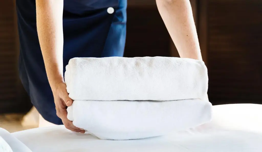 two hands picking up folded bath towels